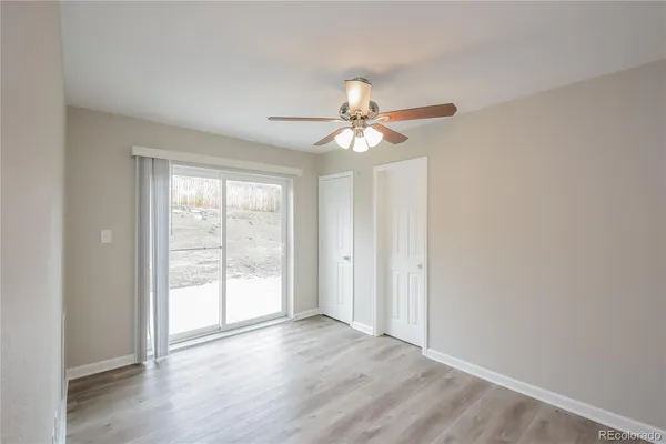 an empty room with wooden floor fan and windows