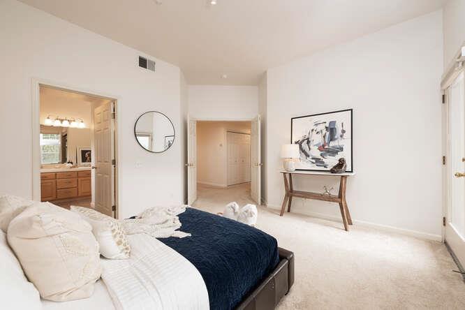 a bedroom with a bed a mirror and paintings on the wall