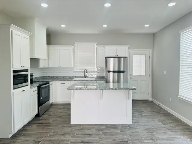 a kitchen with stainless steel appliances granite countertop a white stove top oven and white cabinets