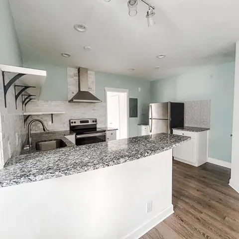 a kitchen with granite countertop a sink and a stove top oven