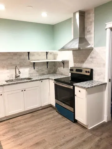a kitchen with stainless steel appliances granite countertop a stove a sink and white cabinets