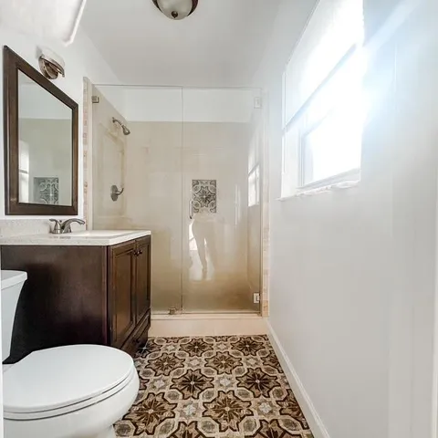 a bathroom with a sink a toilet a mirror and shower