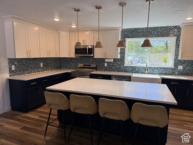 175 North 160 East Hurricane, UT 84737 - Photo 4 of 43 Kitchen featuring a center island, appliances with stainless steel finishes, light stone counters, a textured ceiling, and decorative light fixtures
