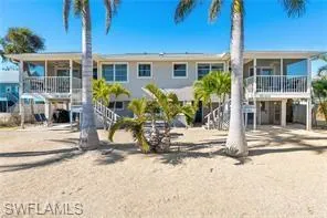 a front view of house with small garden and palm trees