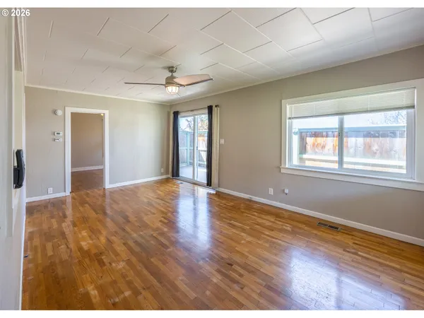 a view of an empty room with wooden floor and a window