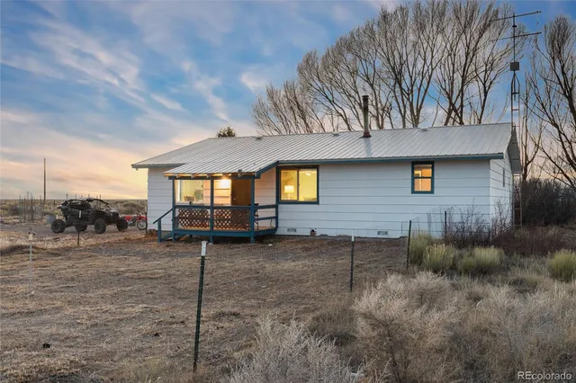a view of a house with a yard and a wooden bench