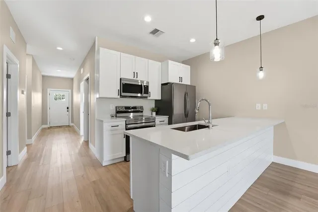 a kitchen with kitchen island a sink stainless steel appliances and wooden floor