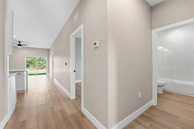 a view of a hallway with wooden floor and a bathroom