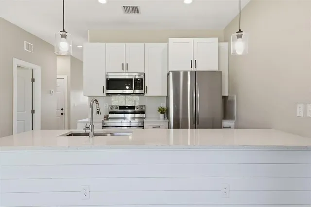a kitchen with kitchen island a counter top space stainless steel appliances and cabinets