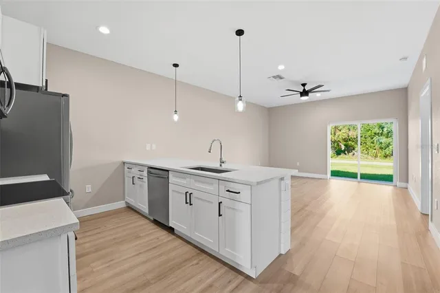 a kitchen with stainless steel appliances granite countertop a sink a stove and a wooden floors