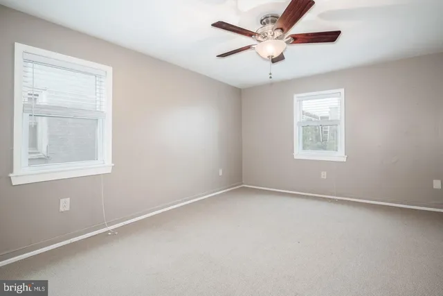 an empty room with a window and a fan