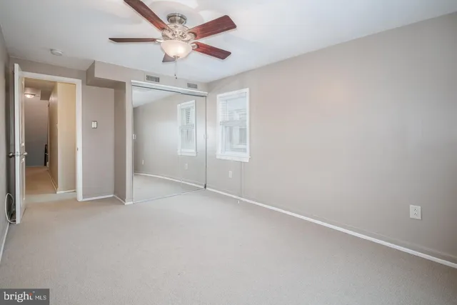 an empty room with chandelier fan and closet area