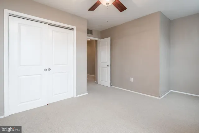 an empty room with closet and a chandelier fan