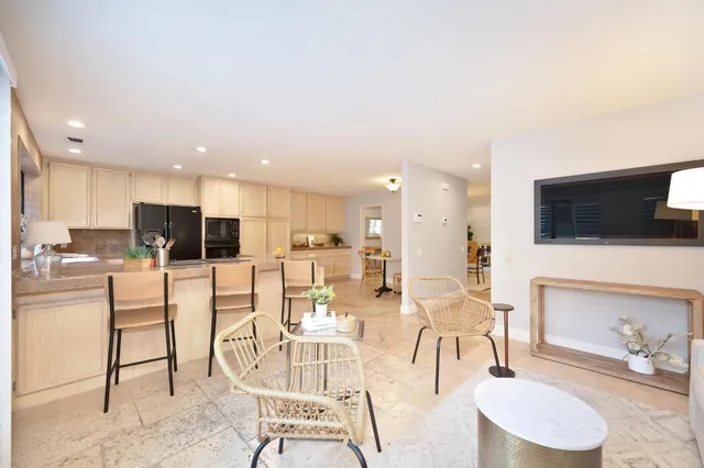a living room with furniture a flat screen tv and kitchen view