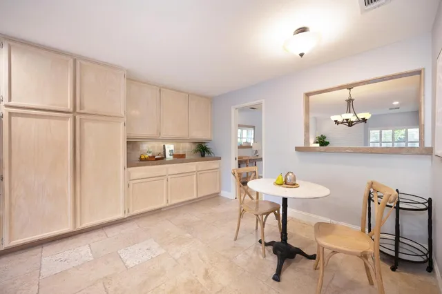 a kitchen with a table chairs a sink dishwasher window and cabinets