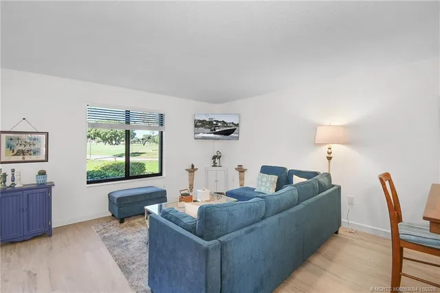 a living room with furniture and a dining table with wooden floor