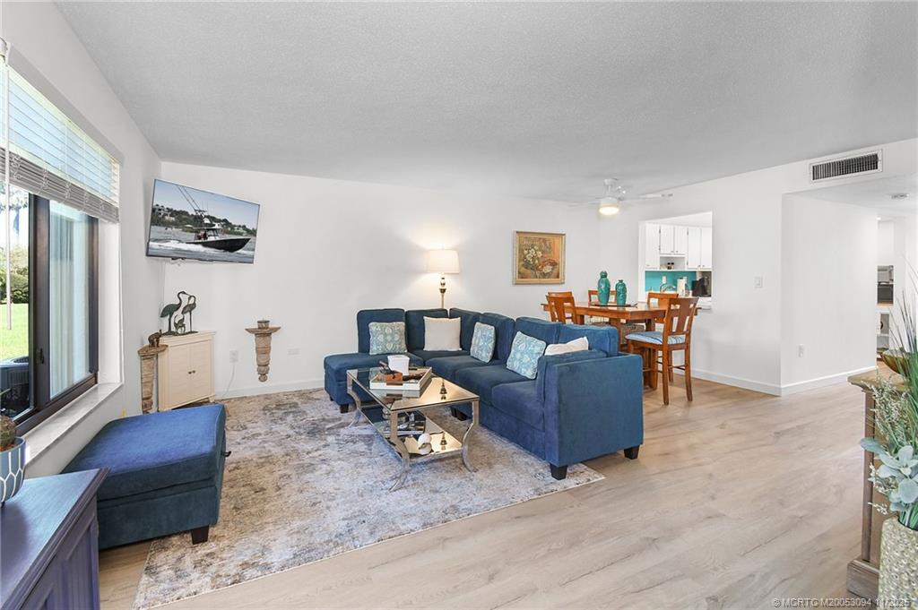5111 Southeast Miles Grant Road, Unit 103 Stuart, FL 34997 - Photo 15 of 59 a living room with furniture and a dining table with wooden floor