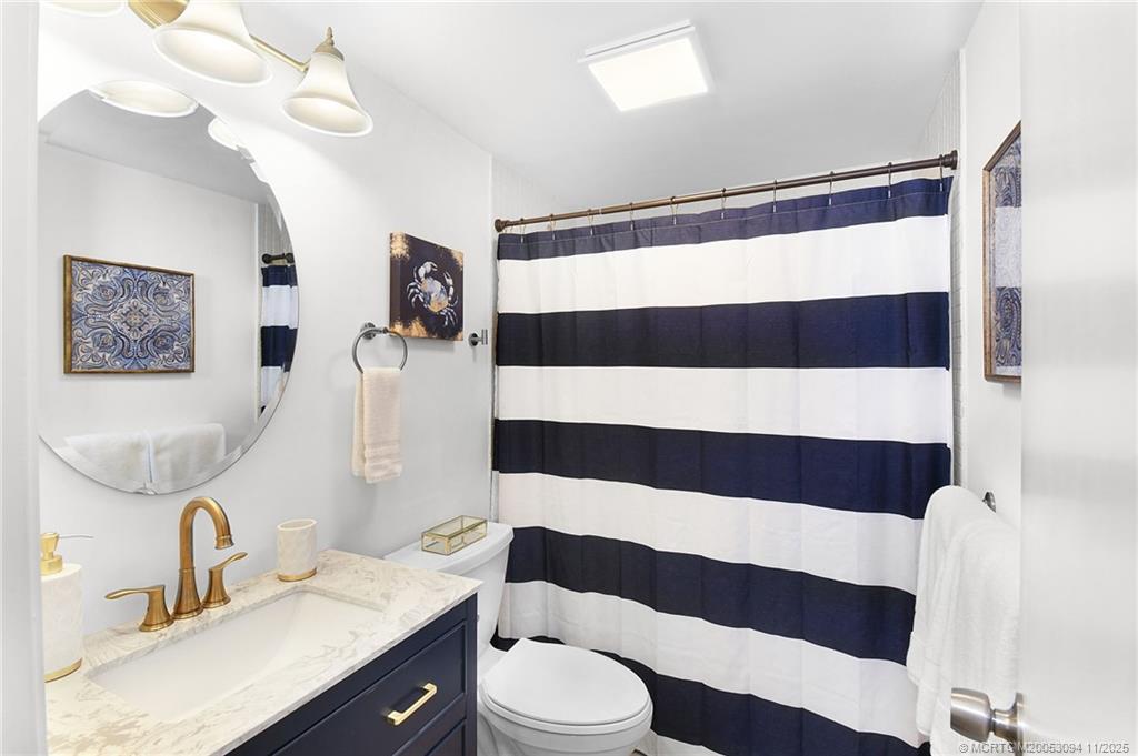 5111 Southeast Miles Grant Road, Unit 103 Stuart, FL 34997 - Photo 23 of 59 a bathroom with a sink a toilet a mirror and shower curtain