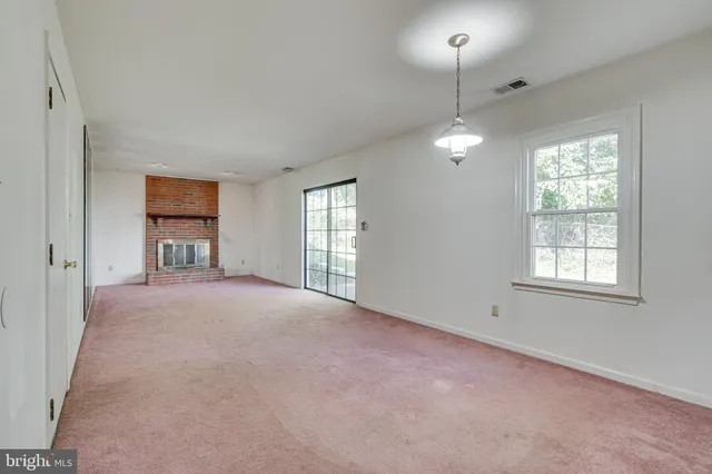 an empty room with windows and chandelier fan