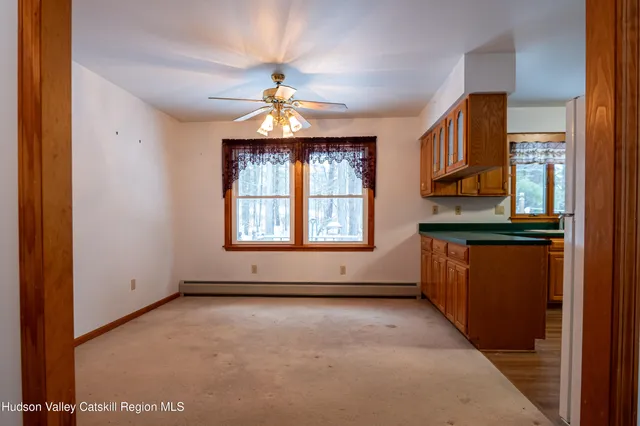 an empty room with windows and chandelier fan