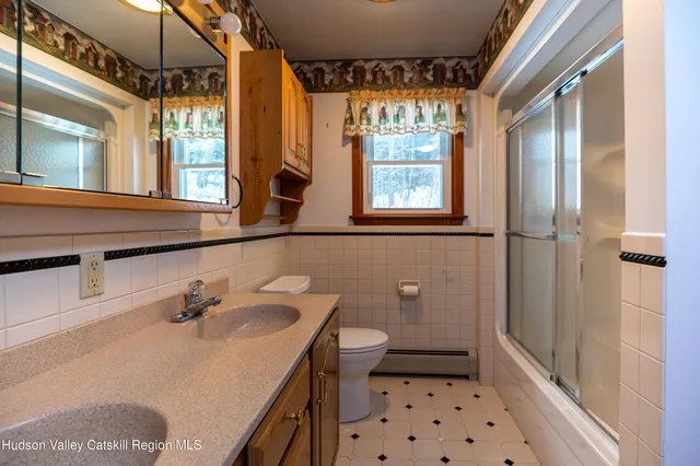 a bathroom with a sink a toilet a shower and a window