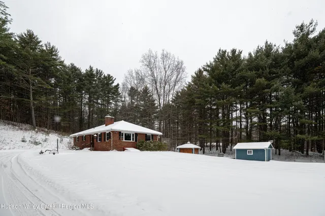 a view of a white house with a yard and covered with snow in the background