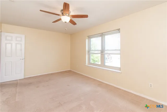 an empty room with windows and fan