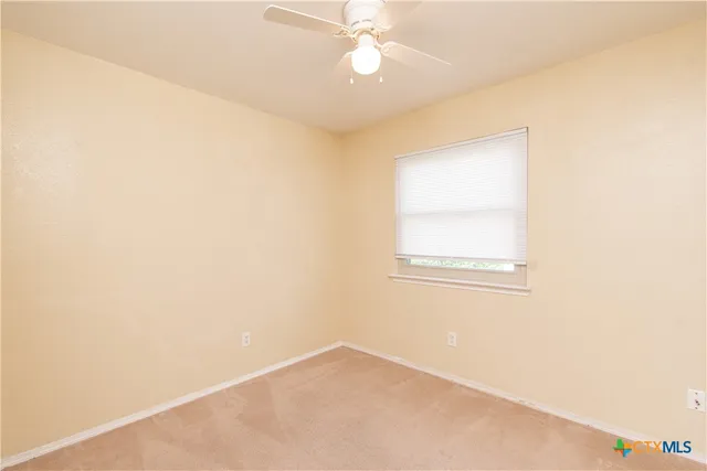 an empty room with a window and a ceiling fan