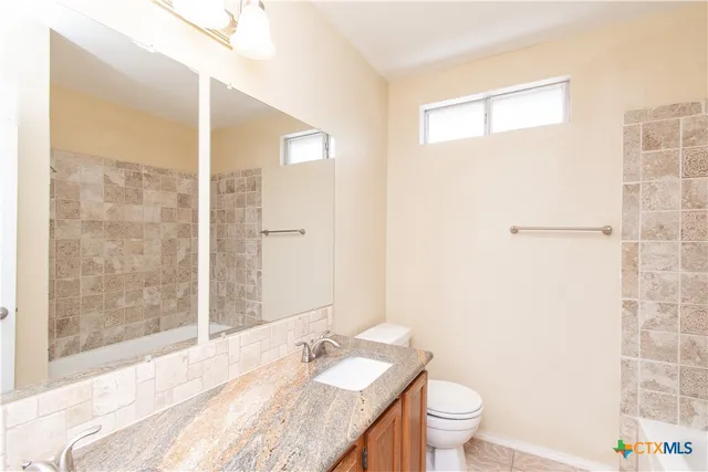 a bathroom with a granite countertop sink a toilet a mirror and shower
