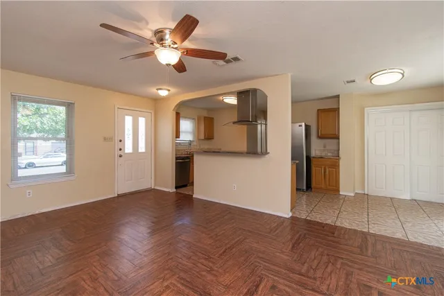 a view of an empty room with window and a kitchen