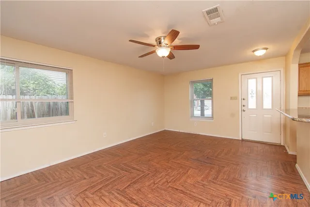 a view of empty room with wooden floor and fan