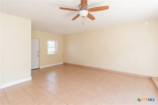 an empty room with windows and fan