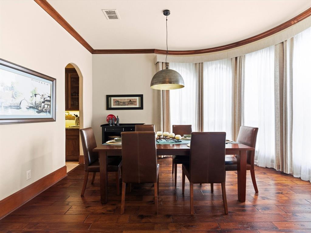 1615 Roma Lane Allen, TX 75013 - Photo 4 of 36 Dining area featuring wood-finish flooring, a contemporary pendant light fixture, and arched window treatments