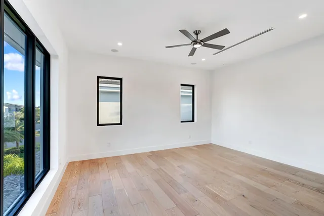 an empty room with wooden floor fan and windows