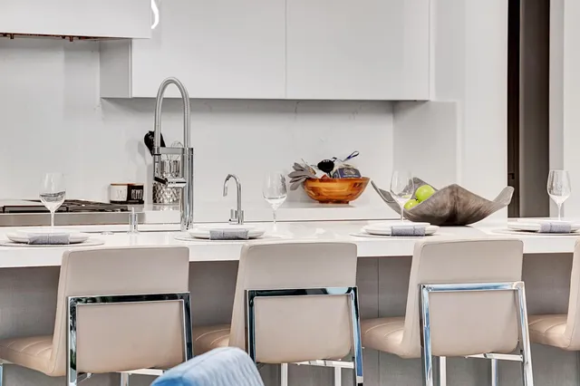 a kitchen with a sink a stove and chairs with cabinets
