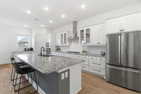 a kitchen with stainless steel appliances granite countertop a kitchen island hardwood floor sink stove and refrigerator