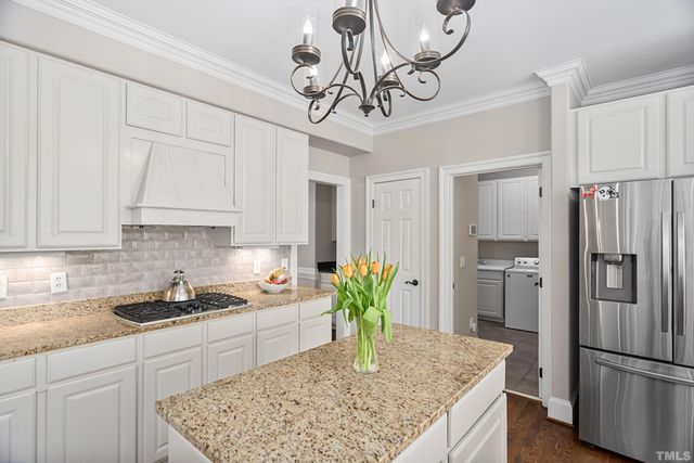a kitchen with stainless steel appliances granite countertop a refrigerator a stove and white cabinets