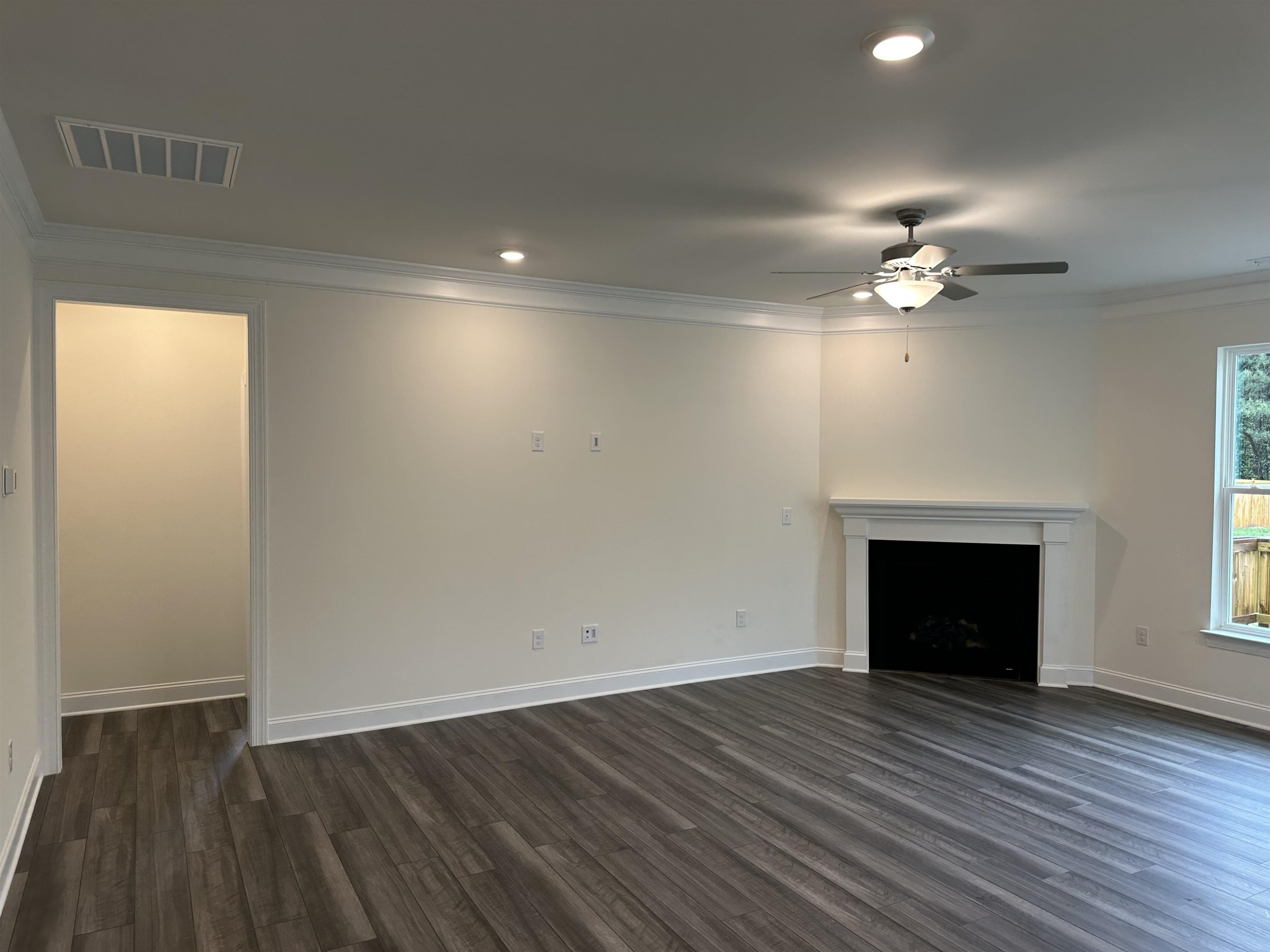 4432 Beckel Road Willow Spring, NC 27592 - Photo 15 of 22 an empty room with wooden floor a chandelier fan and a fireplace