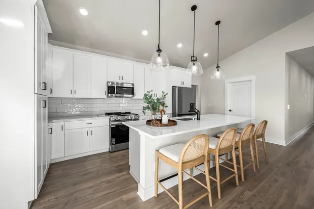 a kitchen with stainless steel appliances kitchen island granite countertop a stove a sink a dining table and chairs with wooden floor