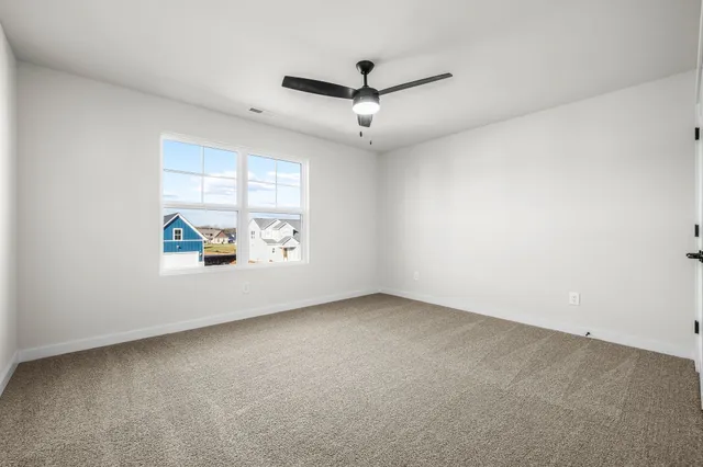 an empty room with ceiling fan and windows