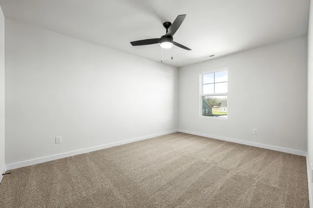 an empty room with a window and a ceiling fan