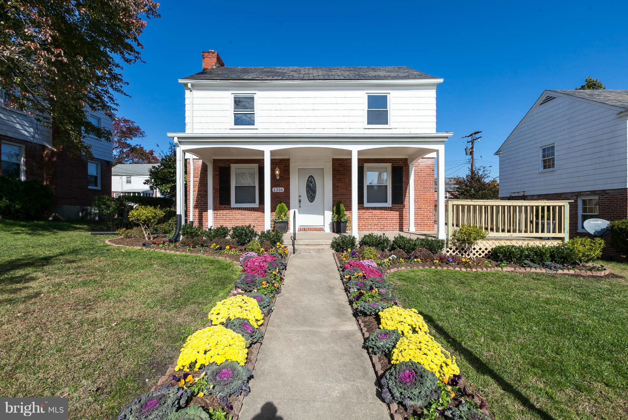 1316 East 35th Street Baltimore, MD 21218 - Photo 5 of 30 a front view of house and yard with beautiful flowers and green space