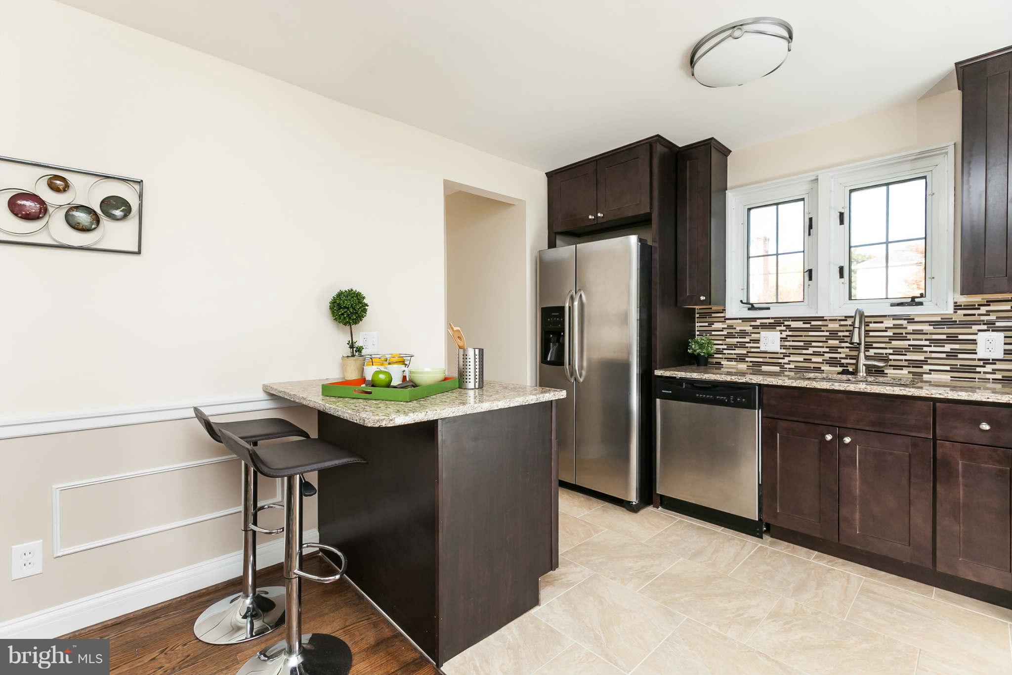 1316 East 35th Street Baltimore, MD 21218 - Photo 7 of 30 a kitchen with stainless steel appliances kitchen island granite countertop a sink cabinets and wooden floor