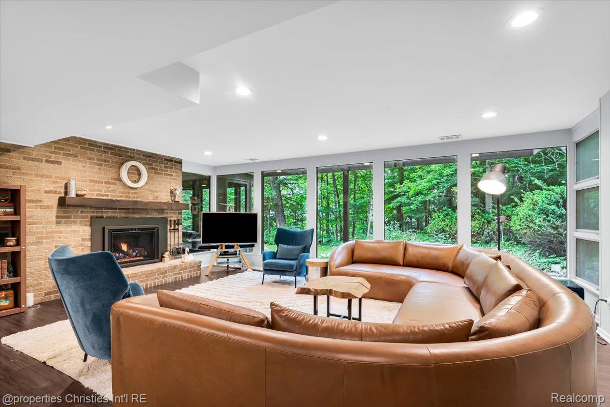 3939 Charing Cross Road Bloomfield Hills, MI 48304 - Photo 27 of 33 Lower level spacious living area featuring a brick fireplace with a wood mantle, built-in shelving, wood-finish flooring, and expansive windows