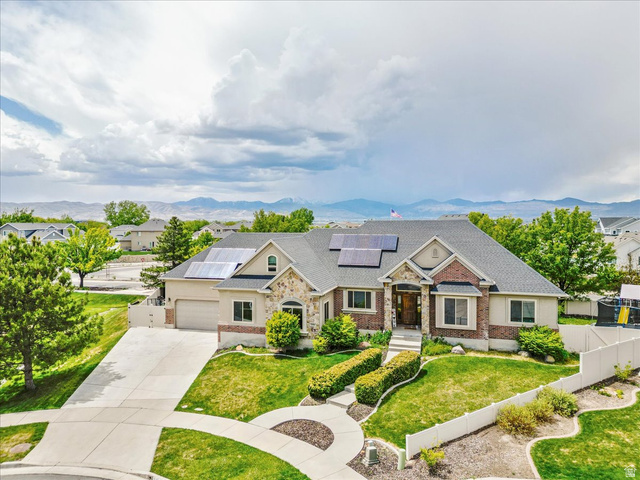 316 Azure Circle Draper, UT 84020 - Photo 4 of 48 Exterior featuring a stone and brick facade, an attached two-car garage, solar panels, a concrete driveway, and established landscaping