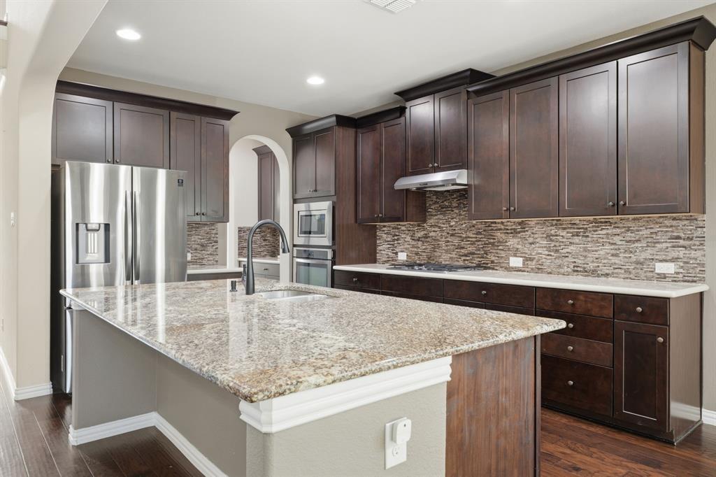 12809 Spring Hill Drive Frisco, TX 75035 - Photo 12 of 37 a kitchen with stainless steel appliances granite countertop a sink refrigerator and cabinets