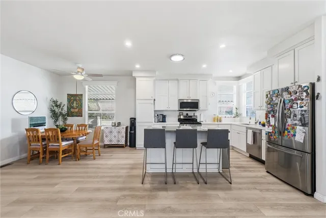 a kitchen with stainless steel appliances kitchen island granite countertop a dining table chairs and refrigerator