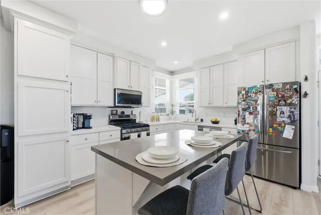 a kitchen with stainless steel appliances a sink a stove a refrigerator cabinets and a dining table