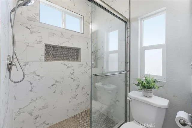 a bathroom with a granite countertop shower a toilet and a sink