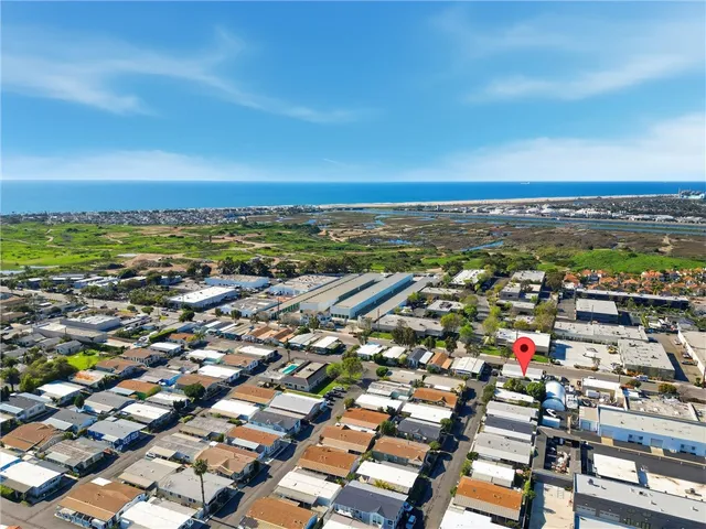 an aerial view of a city with lots of residential buildings and ocean view in back